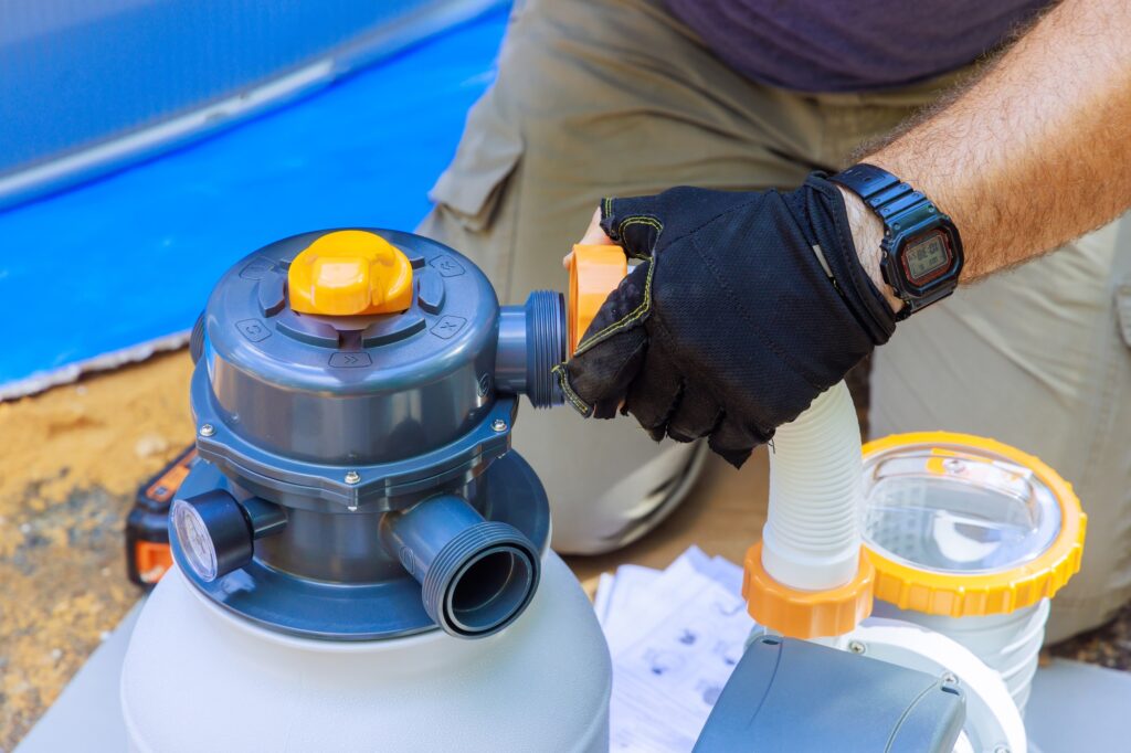 Swimming pool maintenance workers assemble a sand filter system tank cleaning equipment